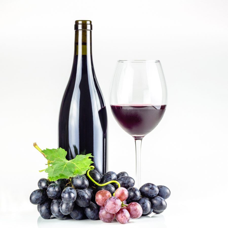 Red wine bottle, wineglass and grapes.